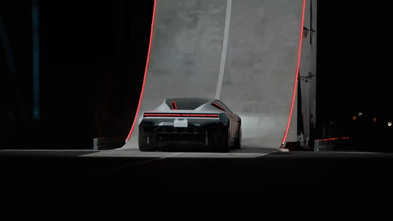 The white Roadster from behind, parked at the foot of a towering curved ramp at night